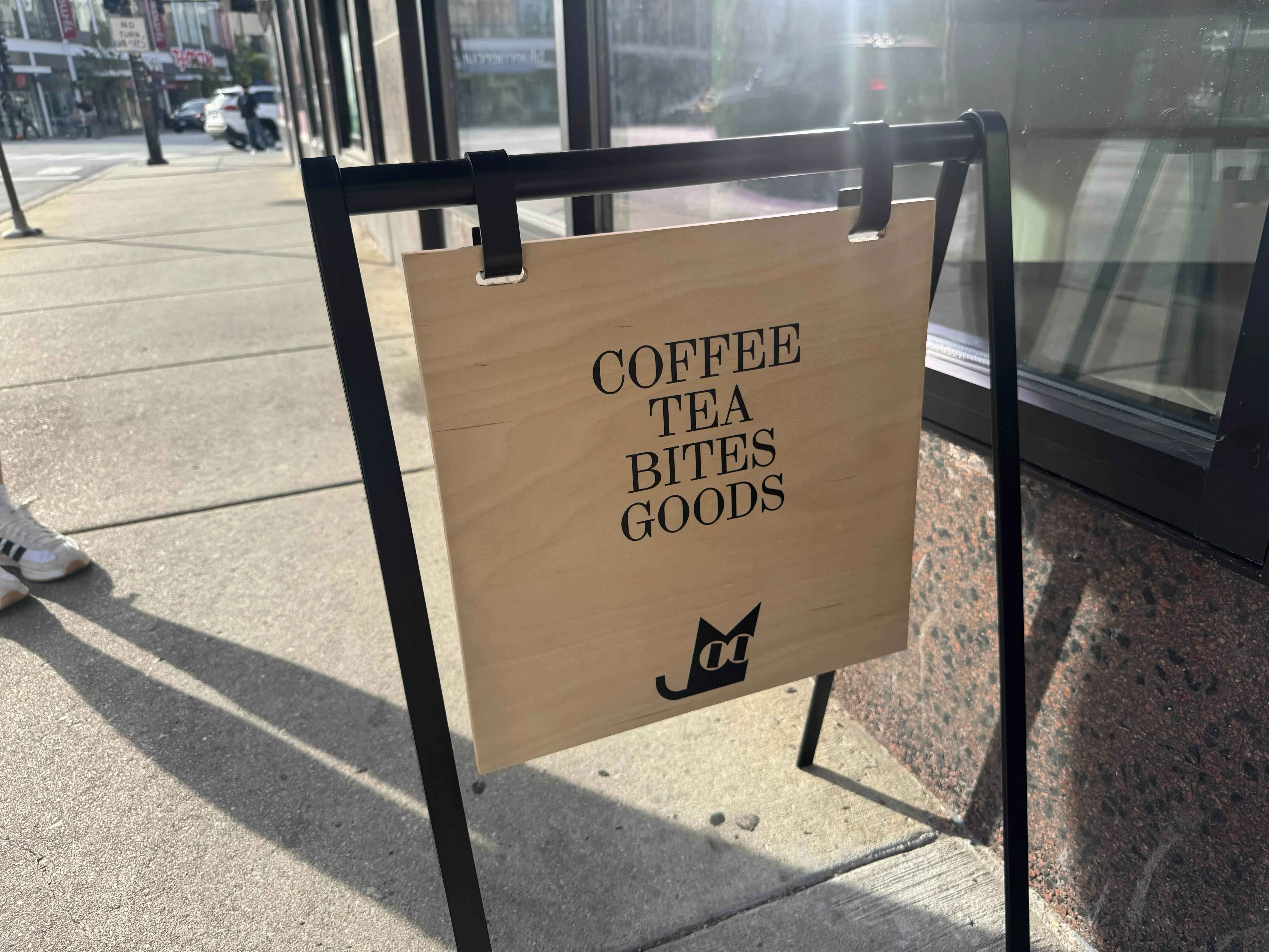 Lucky cat sandwich board. reads "COFFEE TEA BITES GOODS" with a cute abstract cat symbol