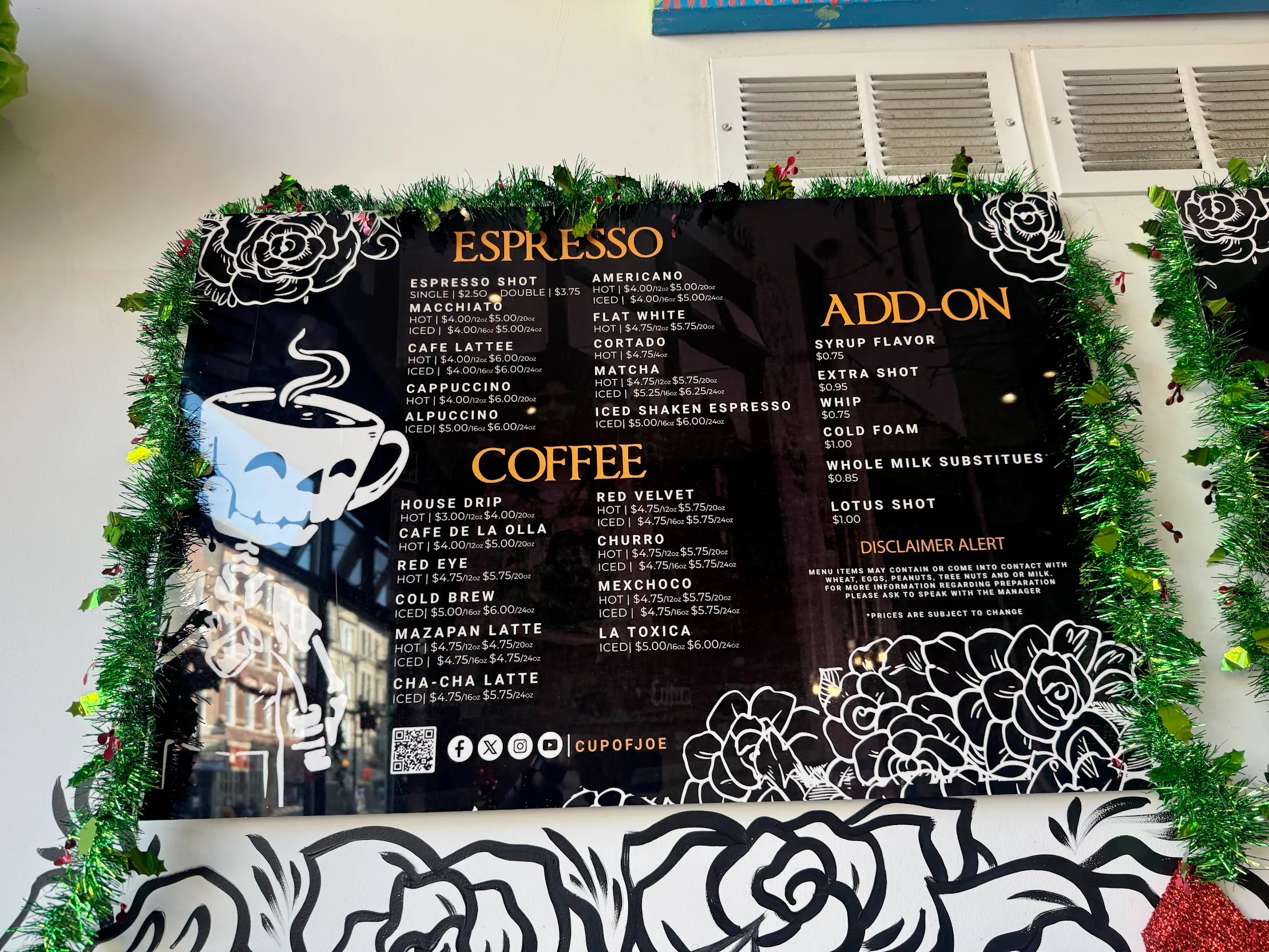 I looove their mascot barista guy Photo of a glossy menu board, with the cafe's signature skeleton character (with steaming espresso cup head) pouring a cuppa