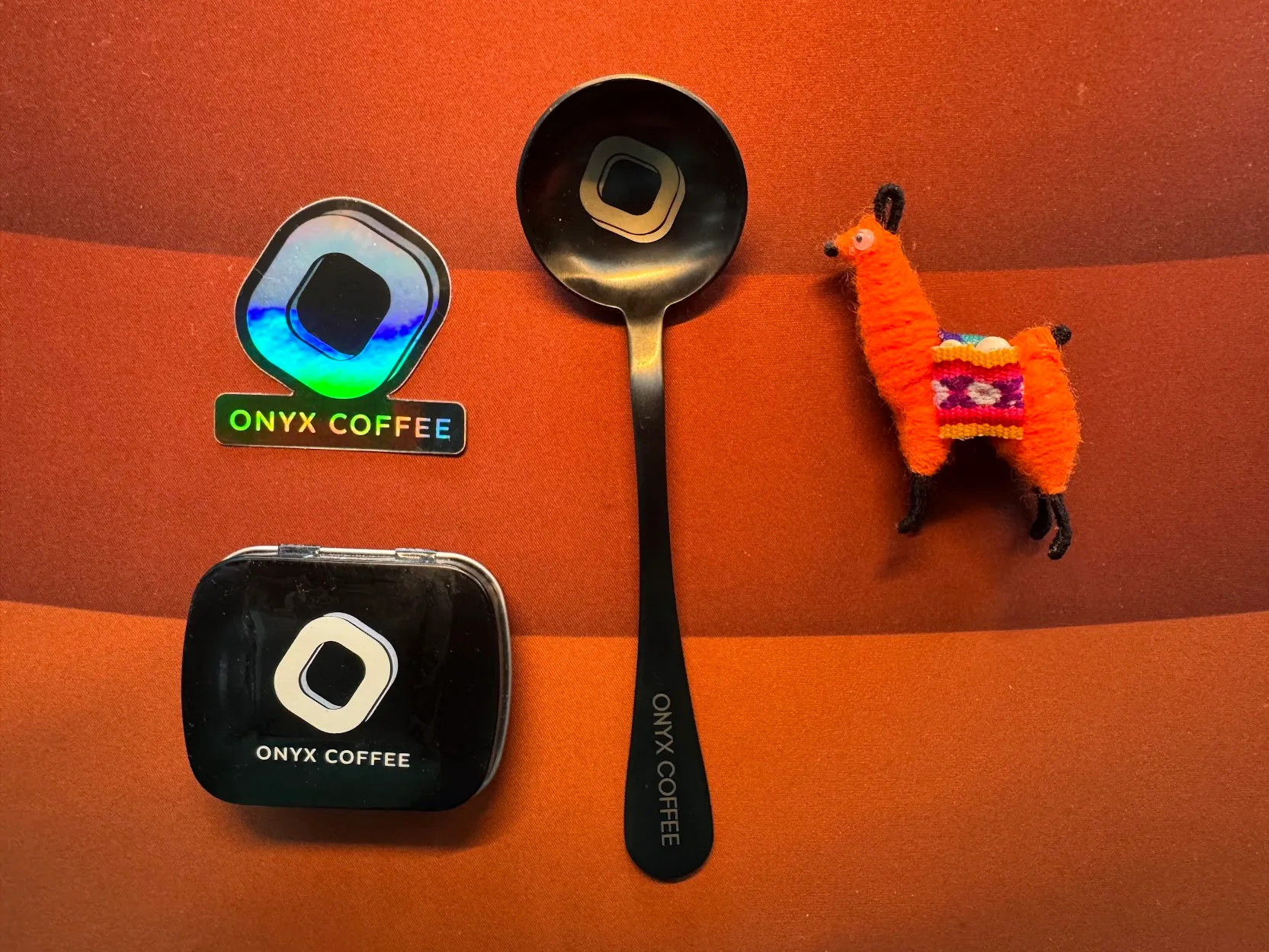 I should've retaken this photo but the orange alpaca almost vanishing into the coffee colored desk mat is kind of iconic My take home items from the event--an orange alpaca, a tasting spoon, a sticker, and a tin of mints on an unfortunate choice for a photo background